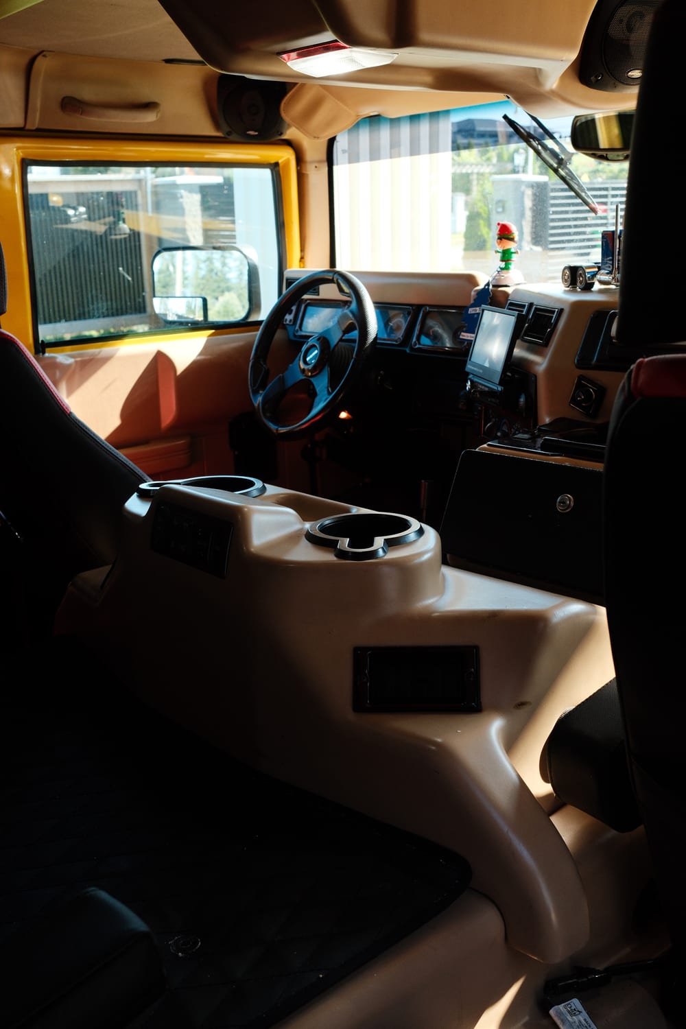 Inside the Hummer H1, showing the tan cabin, the centre console and the steering wheel.